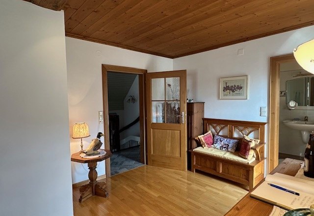 Holzvertäfeltes Zimmer mit Bank, Tischlampe und offenem Zugang zu einem Badezimmer.