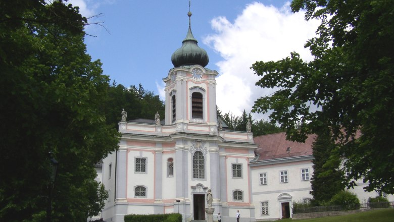 Barockkirche auf dem Mariahilfberg mit grünem Turm und umgeben von Bäumen.
