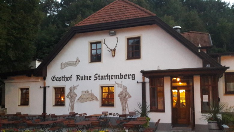 Ein traditionelles Gasthaus mit Au&szlig;enbereich und Wandmalereien, umgeben von B&auml;umen.