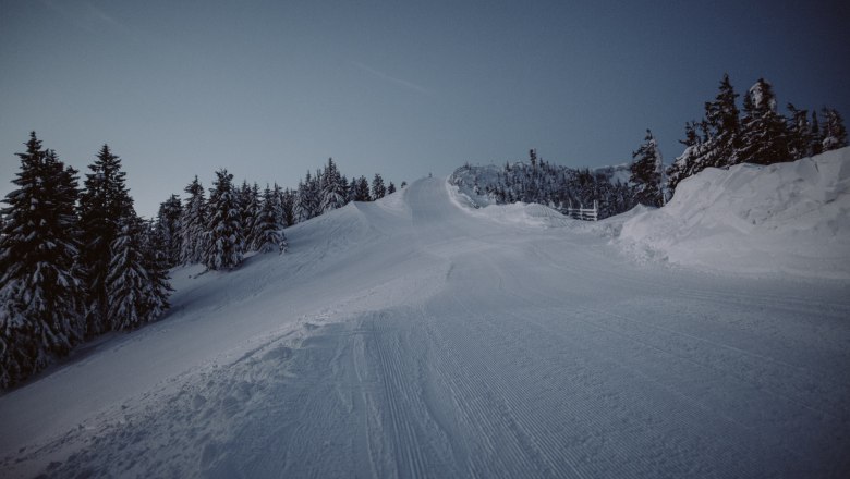 Verschneite Skipiste im Schigebiet Unterberg bei Dämmerung.
