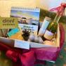 Ein Geschenkkorb mit verschiedenen Wellness-Produkten, darunter ein Kalender, eine Flasche Öl und handgemachte Seifen.