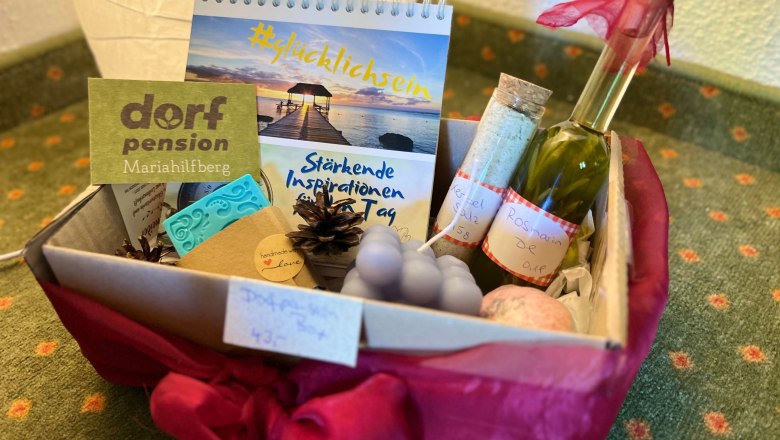 Ein Geschenkkorb mit verschiedenen Wellness-Produkten, darunter ein Kalender, eine Flasche Öl und handgemachte Seifen.