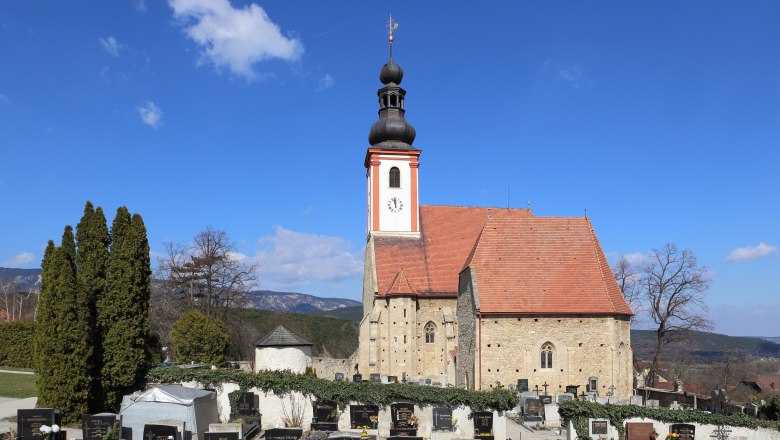 Kirche mit Friedhof im Vordergrund und blauem Himmel.