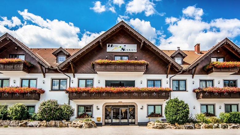 Ein traditionelles Hotel mit Holzbalkonen und Blumenkästen vor einem blauen Himmel.