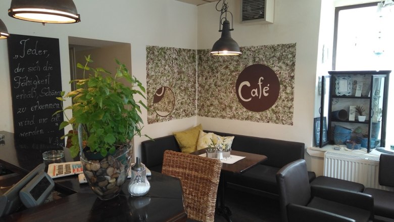 Gemütliches Café mit Pflanzen, Sitzgelegenheiten und Dekorationen.