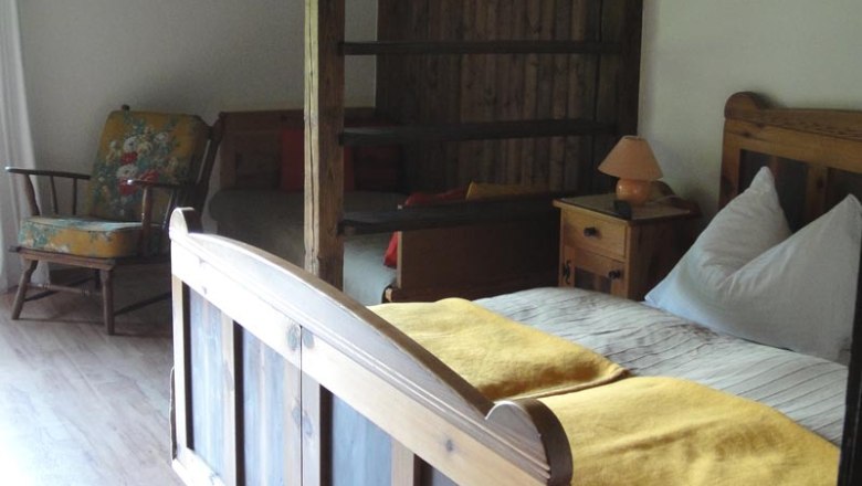 Rustikales Zimmer mit Holzbett, gelber Decke, Schaukelstuhl und Holzwänden.