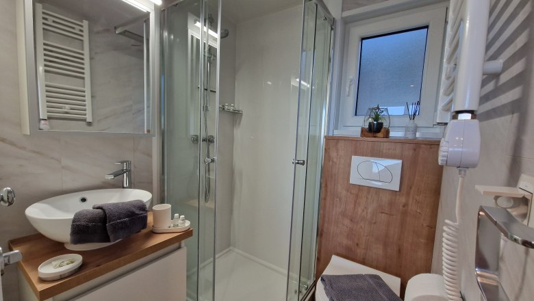 Modernes Badezimmer mit Dusche, Waschbecken und Toilette.