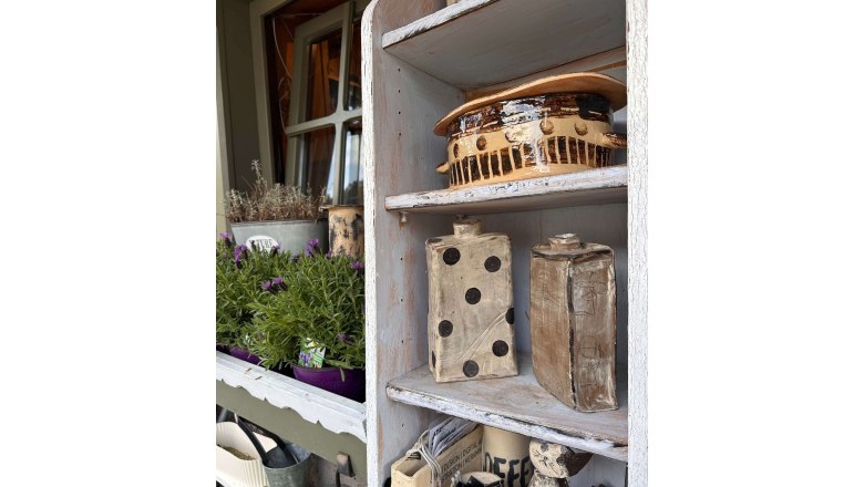 Regal mit Keramikobjekten und Pflanzen in einem Atelier.