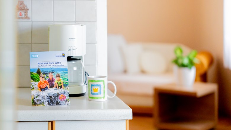 Küchenarbeitsplatte mit Broschüre, Kaffeetasse und Kaffeemaschine.