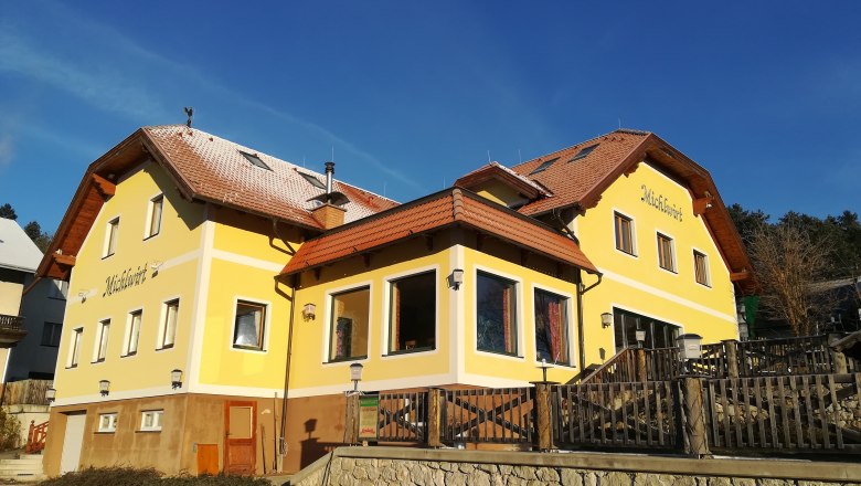 Gelbes Gebäude mit rotem Dach und Schriftzug 'Michlwirt'.