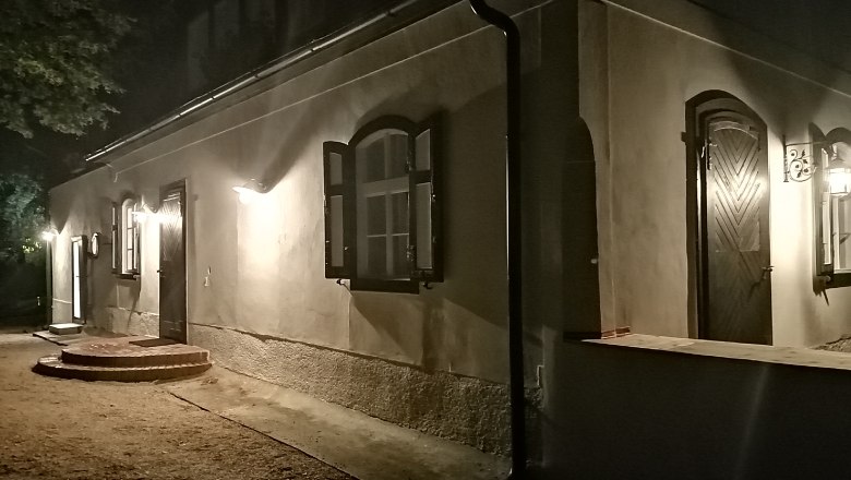 Beleuchtetes Gebäude bei Nacht mit offenen Fenstern und Türen.