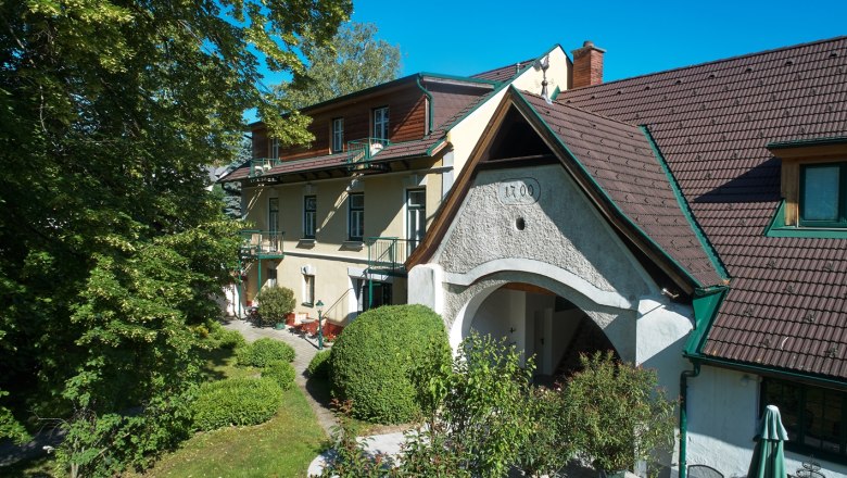 Landhaus Puchbergerhof mit Garten und Bäumen im Vordergrund.