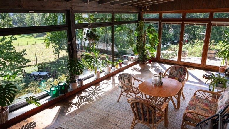 Wintergarten mit Pflanzen und Holzm&ouml;beln, Blick auf Garten.