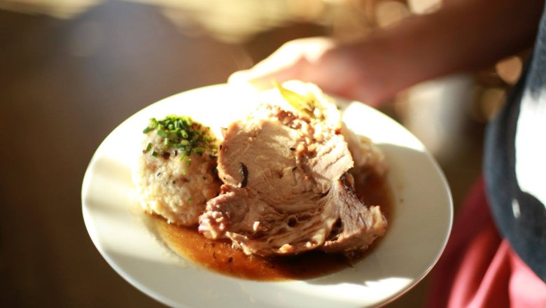 Ein Teller mit Braten, Knödel und Soße.