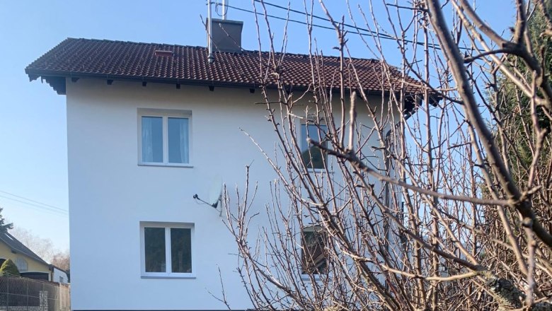 Außenansicht eines weißen Hauses mit rotem Dach und Garten.