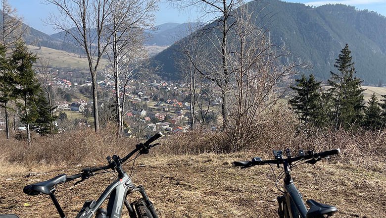 Zwei Fahrräder vor einer Berglandschaft mit Blick auf ein Tal und eine Stadt.