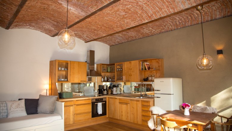 Gemütliche Küche mit Holzmöbeln, Ziegeldecke und Esstisch.