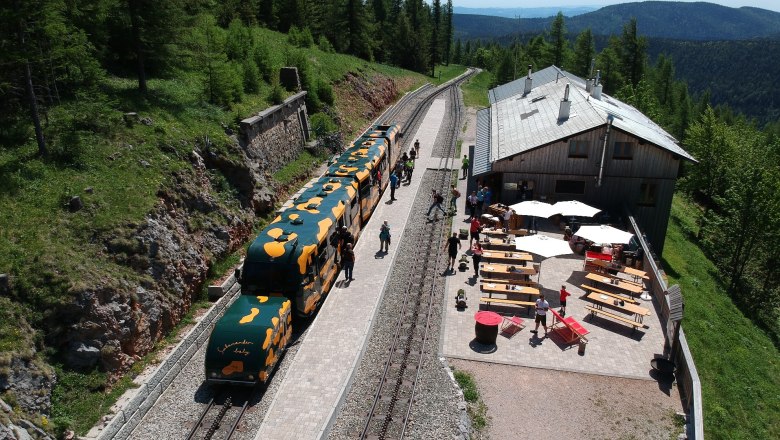 Bergbahnhof mit Zug und Caf&eacute; im Gr&uuml;nen.