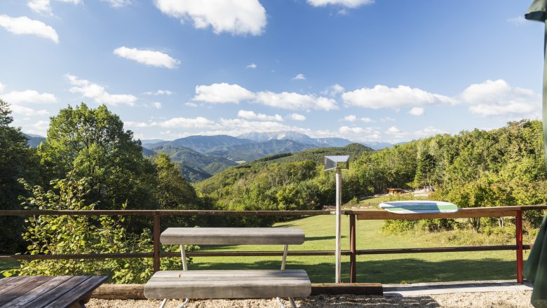 Aussicht vom Waxeneckhaus auf bewaldete Hügel und Berge unter blauem Himmel mit Wolken.