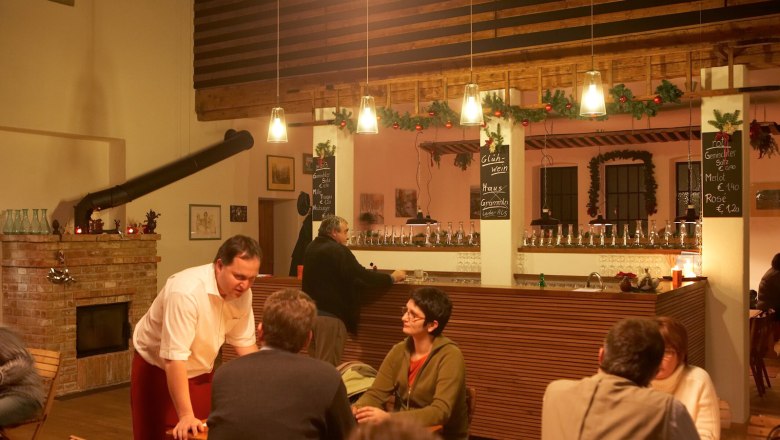 Innenansicht eines gem&uuml;tlichen Lokals mit Bar und G&auml;sten.