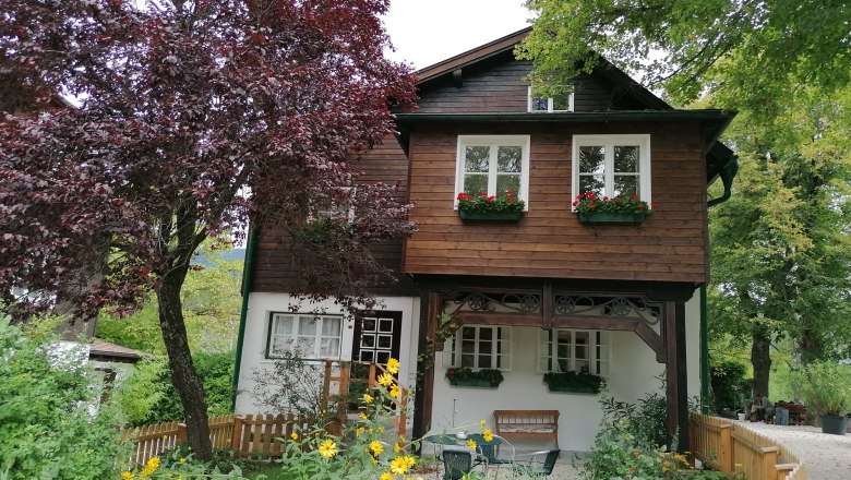 Ein zweistöckiges Holzhaus mit Blumenkästen und Garten.