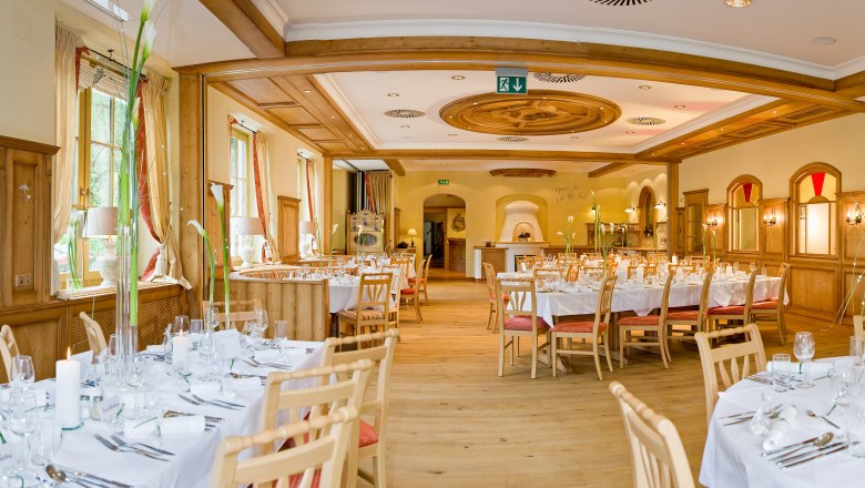 Eleganter Speisesaal mit gedeckten Tischen und Holzverkleidung.