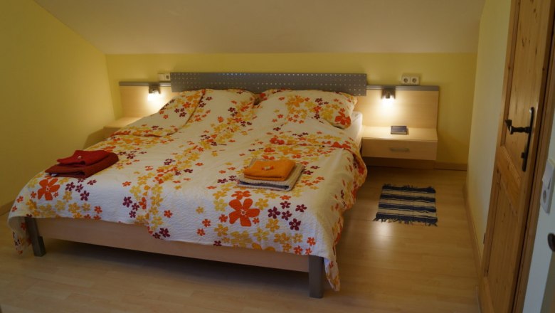 Gemütliches Schlafzimmer mit Doppelbett und Blumenbettwäsche.