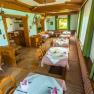 Gemütliches Restaurant mit Holzmöbeln und Tischdecken, dekoriert mit Geweihen an den Wänden.