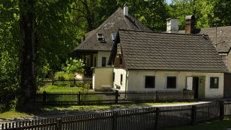 Ein traditionelles Gästehaus mit Holzzaun und Garten, umgeben von Bäumen.