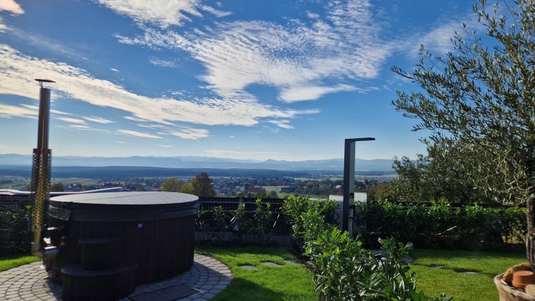 Ein runder Whirlpool im Garten mit Blick auf eine weite Landschaft und blauen Himmel.
