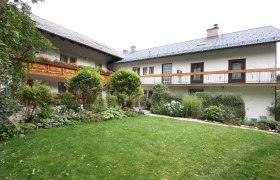 Ein traditionelles Haus mit Holzbalkon und gepflegtem Garten.