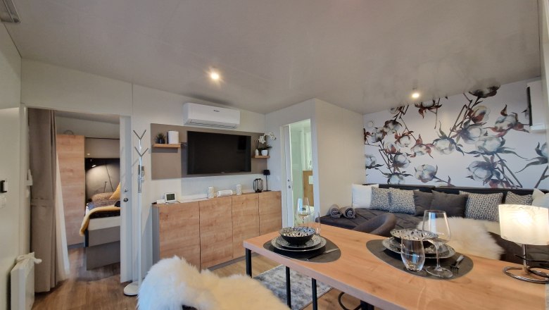 Modernes Wohnzimmer mit Esstisch, Sofa und dekorativer Wand.