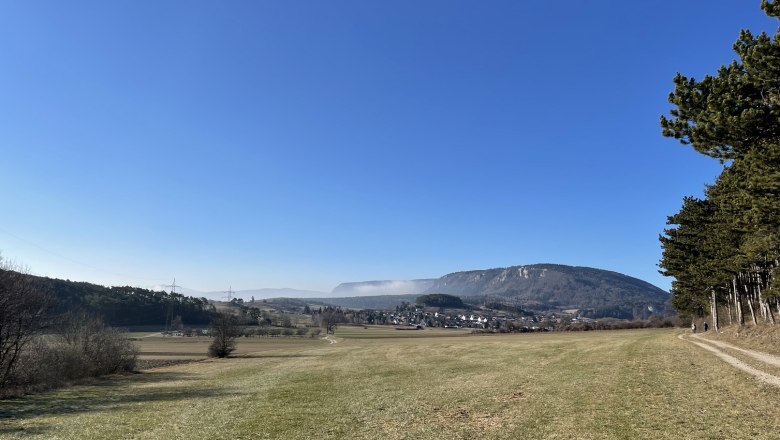 Landschaft mit Wiese, Hügeln und klarem Himmel.