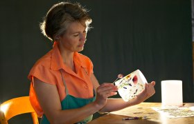 Frau dekoriert eine Laterne mit gepressten Blumen.