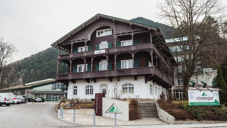 Hotel Schneeberghof in einer bergigen Umgebung mit traditioneller Architektur und einem großen Schild vor dem Gebäude.