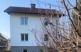 Außenansicht eines weißen Hauses mit rotem Dach und Garten.