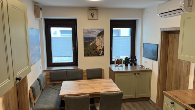 Moderne Küche mit Holzmöbeln, Esstisch und grünen Schränken.