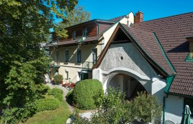Landhaus Puchbergerhof mit Garten und B&auml;umen im Vordergrund.