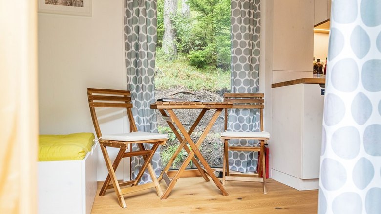 Gemütlicher Sitzbereich mit Holzmöbeln und Blick ins Grüne.