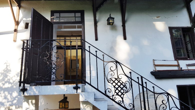 Eingangsbereich eines Hauses mit Treppe und schmiedeeisernem Geländer.