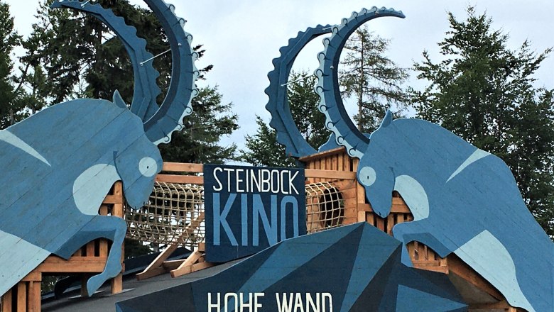 Holzskulpturen von Steinböcken mit der Aufschrift 'Steinbock Kino Hohe Wand'.